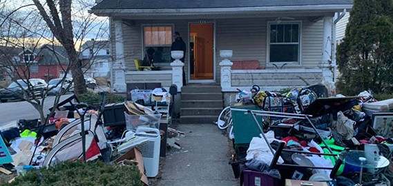 Front of a house with trash all over the lawn