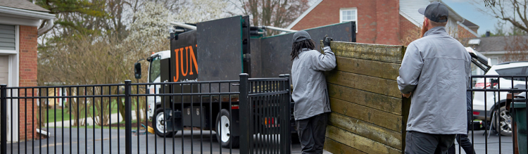 JunkCo workers moving hot tub flooring into truck