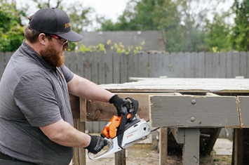 Worker cutting deck section with a chainsaw